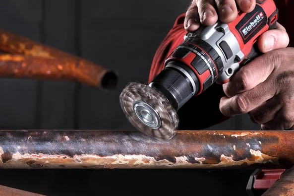 Person entfernt Rost von Metall